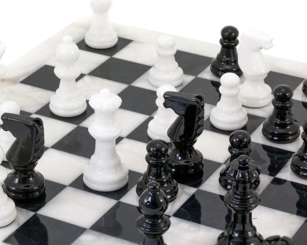 Close-up of a black and white alabaster chess set in the middle of a game, beautifully crafted and polished for a high sheen finish.