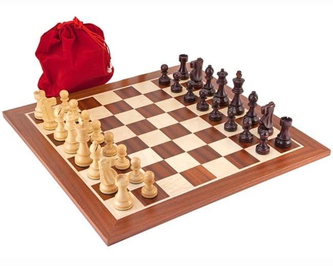 Antiqued British Mahogany chess set with Staunton pieces on a mahogany and maple board, alongside a red drawstring bag.