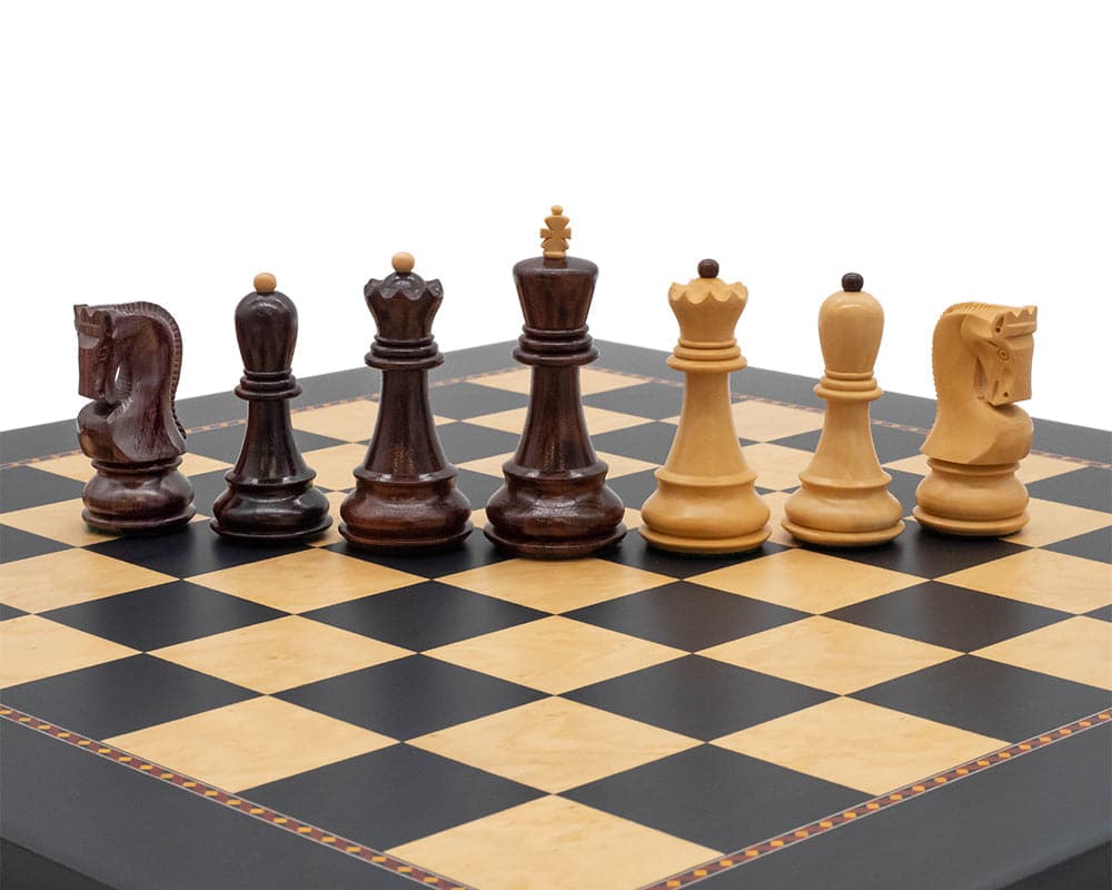 The Queens Gambit chess set on a dark board with decorative border, featuring black and white detailed chess pieces.